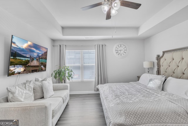 bedroom featuring baseboards, a ceiling fan, dark wood finished floors, and a tray ceiling