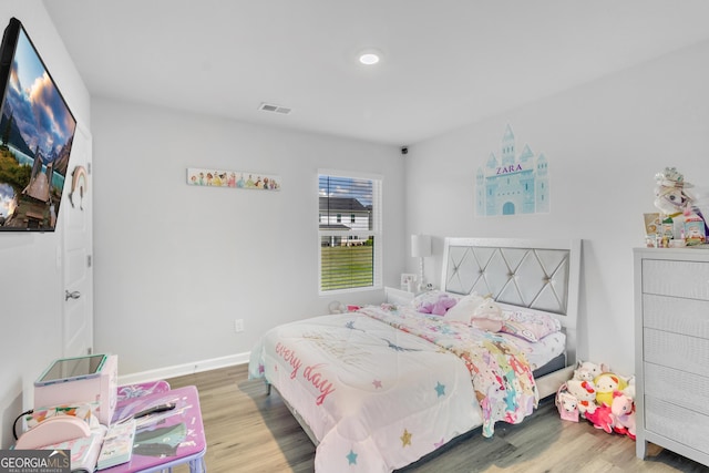 bedroom with visible vents, baseboards, and wood finished floors