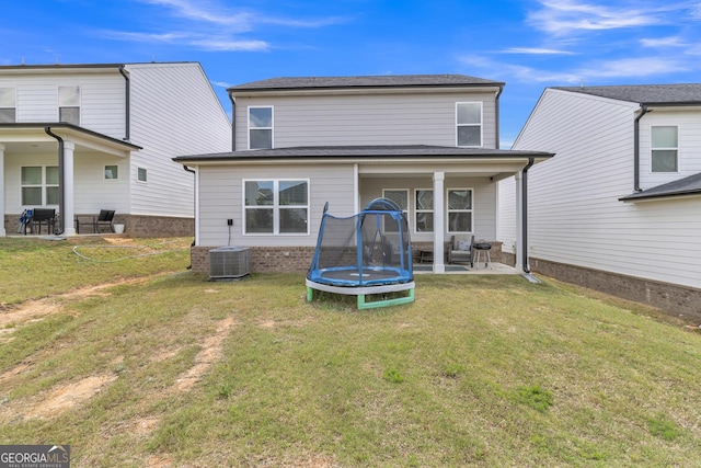 rear view of house featuring a lawn, a trampoline, and a patio area