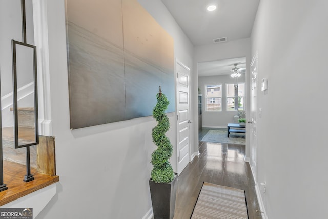hallway with visible vents, baseboards, and dark wood-style floors