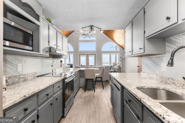 109 Shelton Ln, Eatonton, GA 31024 - kitchen with appliances with stainless steel finishes, gray cabinets, light wood-style flooring, lofted ceiling, and a sink