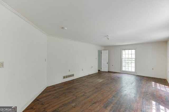 empty room with visible vents, crown molding, and wood-type flooring