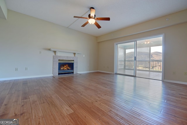 3112 Allison Ct, Young Harris, GA 30582 - unfurnished living room with baseboards, a tiled fireplace, wood finished floors, and a ceiling fan
