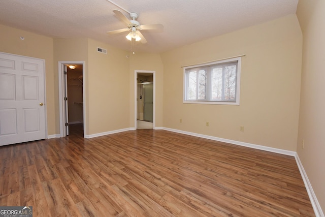 3112 Allison Ct, Young Harris, GA 30582 - unfurnished bedroom with wood finished floors, a walk in closet, a textured ceiling, baseboards, and visible vents