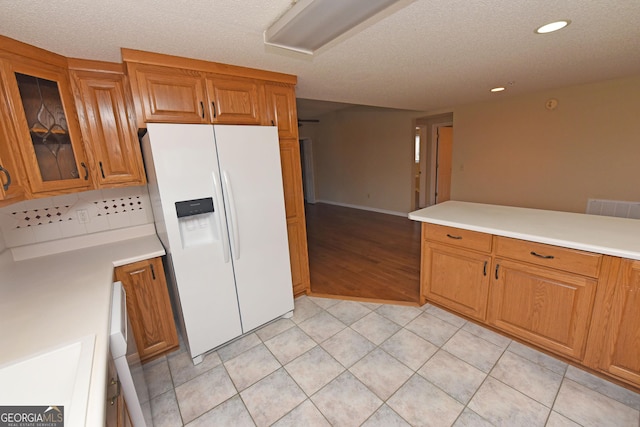 3112 Allison Ct, Young Harris, GA 30582 - kitchen featuring light countertops, white refrigerator with ice dispenser, glass insert cabinets, brown cabinetry, and light tile patterned floors