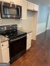 370 Rainey Dr, Dawsonville, GA 30534 - kitchen with a wainscoted wall, white cabinets, tasteful backsplash, black electric range, and dark wood-style flooring