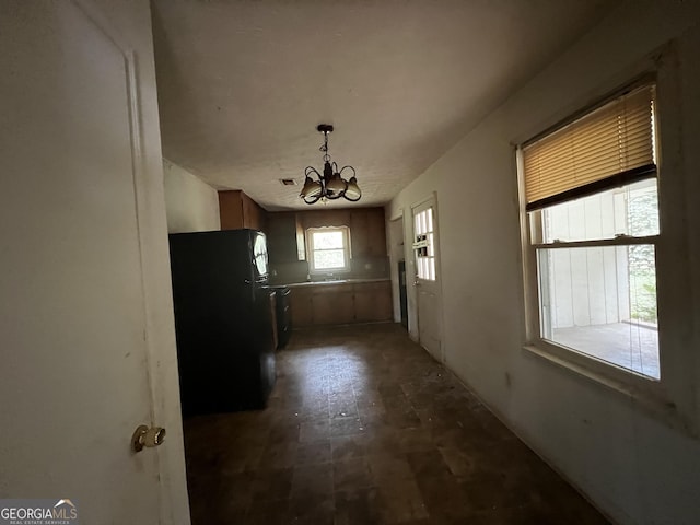 kitchen with freestanding refrigerator, a notable chandelier, decorative light fixtures, and brown cabinets