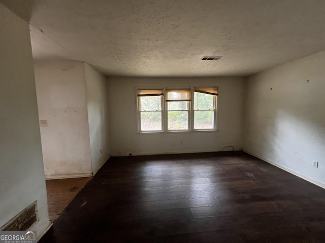 unfurnished room featuring baseboards, visible vents, hardwood / wood-style flooring, and a textured ceiling