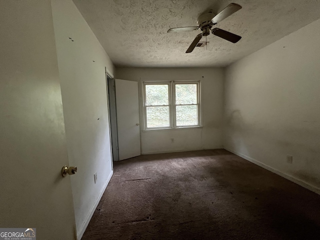 spare room with a textured ceiling, carpet flooring, ceiling fan, and baseboards