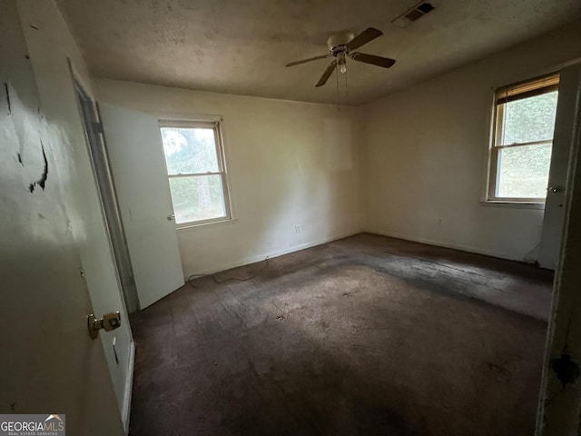 empty room featuring plenty of natural light, visible vents, and ceiling fan