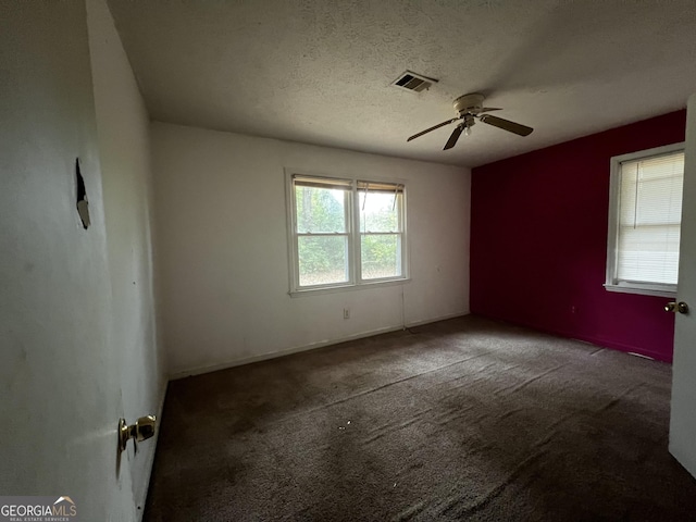empty room with a textured ceiling, visible vents, carpet, and a ceiling fan