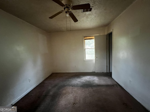 spare room featuring a textured ceiling, concrete floors, and ceiling fan