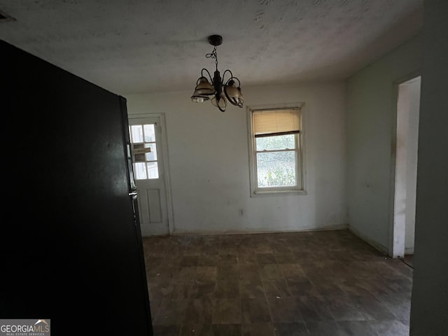 unfurnished dining area with plenty of natural light, wood finished floors, and an inviting chandelier