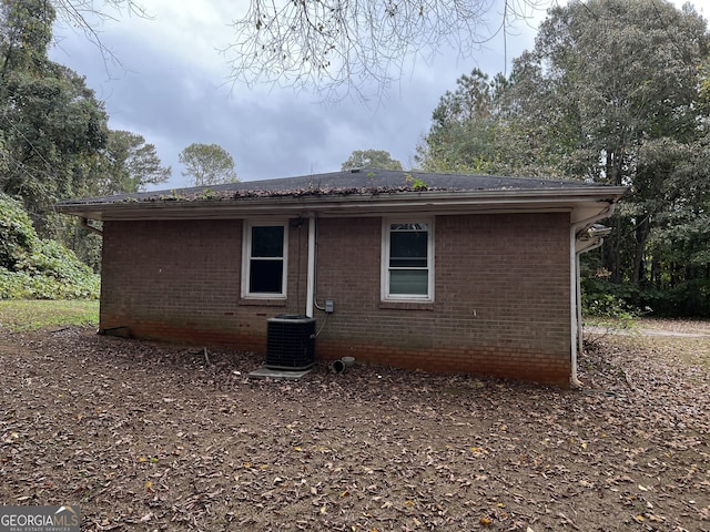 back of property featuring brick siding and central AC