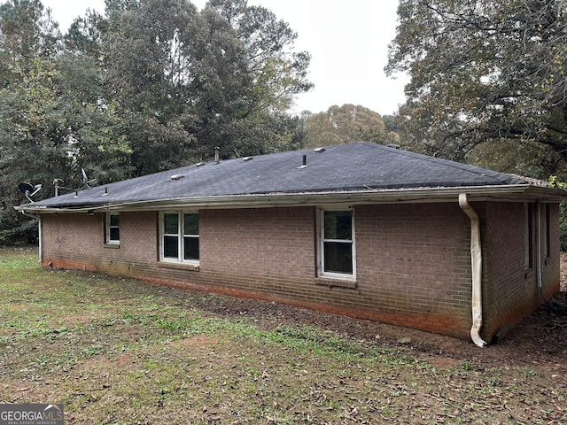 view of home's exterior with a shingled roof and brick siding