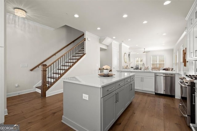 kitchen featuring a peninsula, a sink, dark wood-type flooring, appliances with stainless steel finishes, and a kitchen island