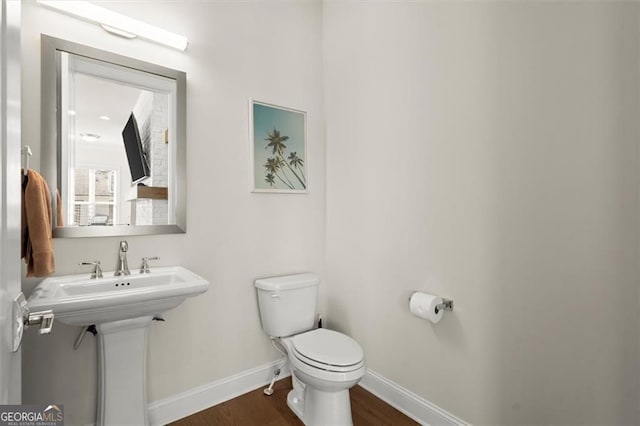 half bath featuring toilet, baseboards, and wood finished floors