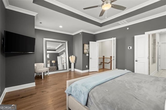 bedroom featuring a tray ceiling, recessed lighting, ornamental molding, visible vents, and wood finished floors