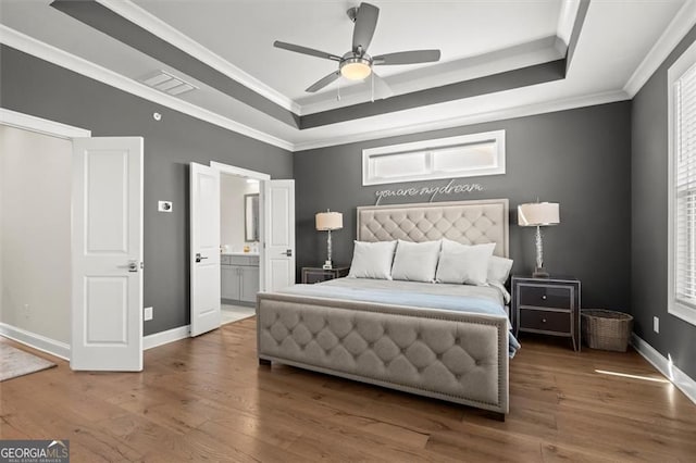 bedroom with a raised ceiling, baseboards, multiple windows, and wood finished floors