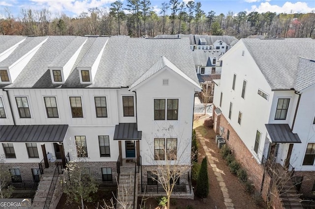 view of front of house featuring brick siding, roof with shingles, and a standing seam roof