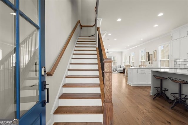 staircase featuring ornamental molding, recessed lighting, and wood finished floors