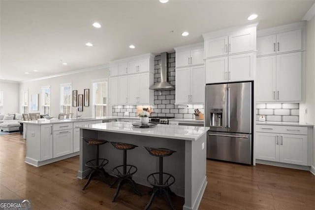 kitchen featuring a center island, open floor plan, wall chimney range hood, appliances with stainless steel finishes, and ornamental molding