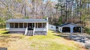view of front facade featuring a detached carport, a front lawn, and gravel driveway