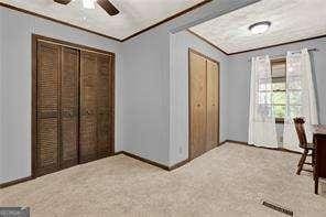 bedroom with a closet, crown molding, carpet, and baseboards