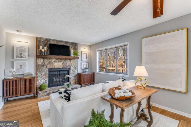 4519 Glenforest Dr NE, Roswell, GA 30075 - living area with wood finished floors, a textured ceiling, a stone fireplace, baseboards, and ceiling fan