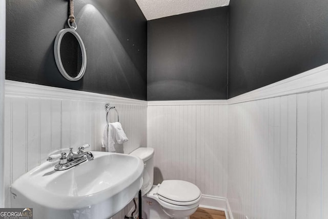 4519 Glenforest Dr NE, Roswell, GA 30075 - bathroom with a wainscoted wall, a textured ceiling, toilet, wood finished floors, and a sink