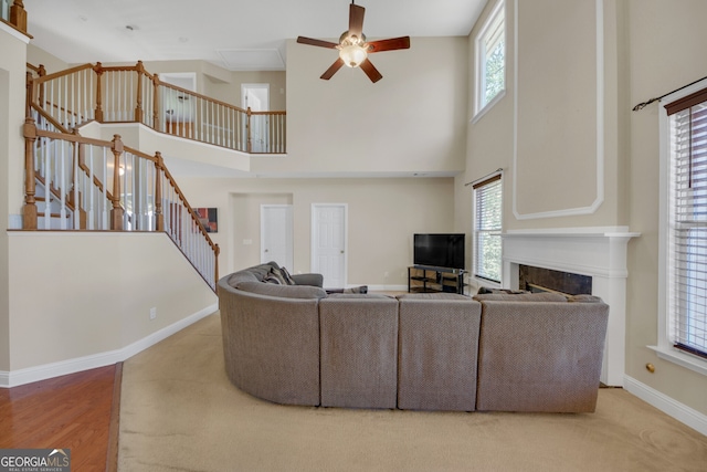 1210 Spring Branch Ct, Lawrenceville, GA 30045 - carpeted living room featuring a ceiling fan, stairs, a towering ceiling, and a premium fireplace