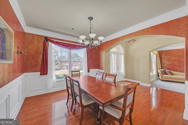 1210 Spring Branch Ct, Lawrenceville, GA 30045 - dining area featuring arched walkways, plenty of natural light, a chandelier, wood finished floors, and crown molding