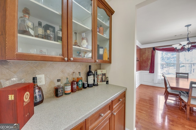 1210 Spring Branch Ct, Lawrenceville, GA 30045 - bar with light wood-type flooring, a chandelier, decorative backsplash, wainscoting, and hanging light fixtures