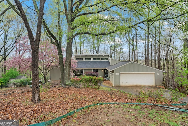 mid-century inspired home featuring driveway, a garage, and roof with shingles