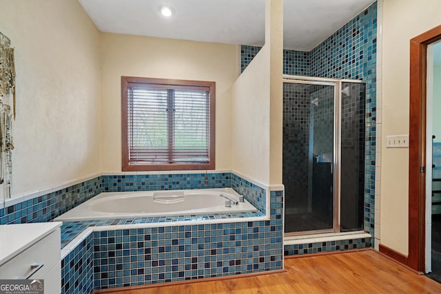 full bath featuring wood finished floors, a garden tub, and a shower stall