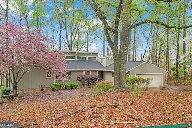 mid-century modern home featuring a garage and roof with shingles
