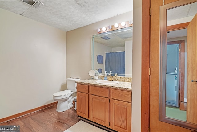 full bathroom featuring vanity, toilet, baseboards, visible vents, and wood finished floors