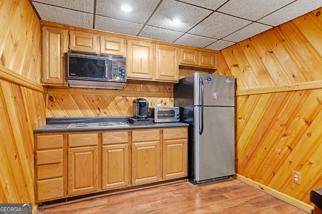 kitchen with freestanding refrigerator, dark countertops, and wood walls