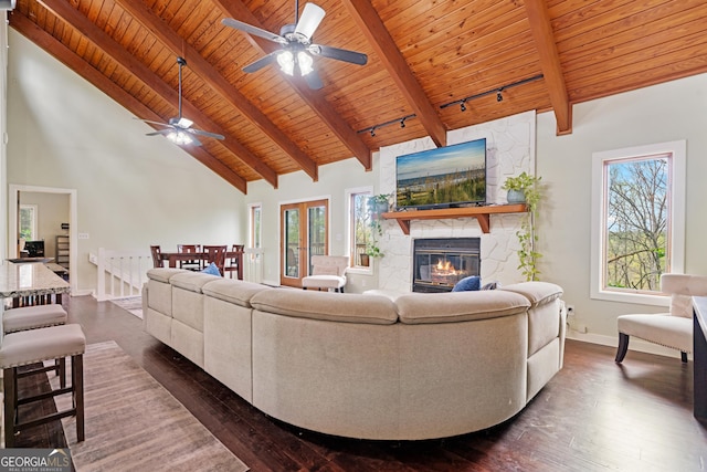 living area with dark wood-style floors, high vaulted ceiling, a ceiling fan, and a stone fireplace