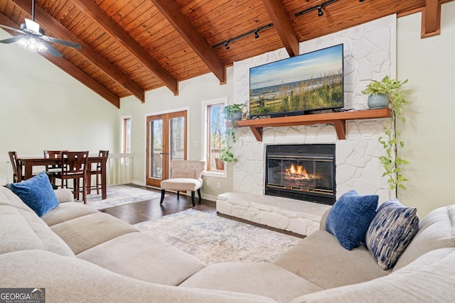 living room featuring rail lighting, a fireplace, wood finished floors, beam ceiling, and wood ceiling