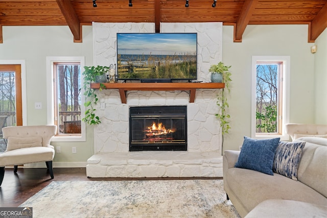 living area with wooden ceiling, beamed ceiling, a fireplace, and wood finished floors
