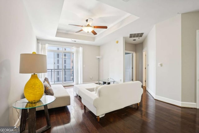 living room featuring a ceiling fan, a raised ceiling, hardwood / wood-style flooring, and baseboards