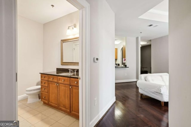 bathroom featuring vanity, toilet, baseboards, visible vents, and wood finished floors