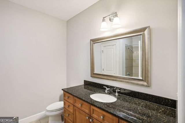 bathroom with a shower, vanity, toilet, baseboards, and tile patterned floors