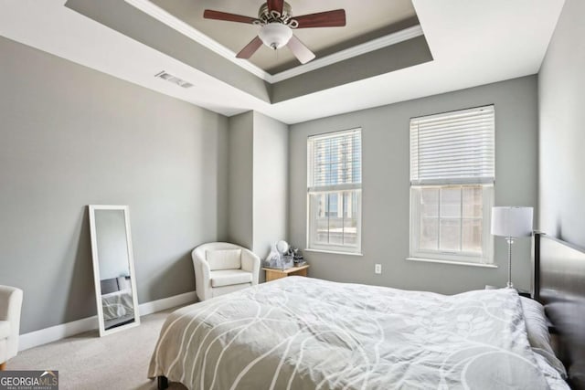 carpeted bedroom with crown molding, a raised ceiling, baseboards, visible vents, and ceiling fan