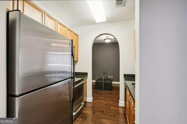 kitchen with light brown cabinetry, appliances with stainless steel finishes, dark wood finished floors, visible vents, and arched walkways