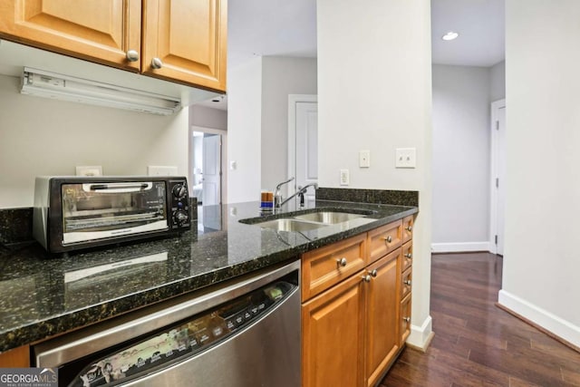 kitchen with dark stone countertops, a toaster, a sink, dark wood-style floors, and dishwasher