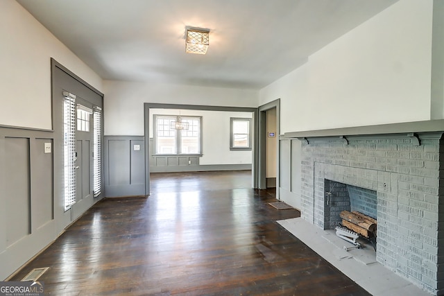 1497 Rogers Ave SW, Atlanta, GA 30310 - unfurnished living room featuring a decorative wall, healthy amount of natural light, dark wood finished floors, a wainscoted wall, and a fireplace