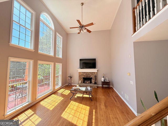 5045 Southern Trace Dr, Gainesville, GA 30504 - living room with a towering ceiling, a stone fireplace, hardwood / wood-style flooring, a ceiling fan, and baseboards
