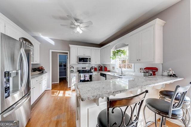 5045 Southern Trace Dr, Gainesville, GA 30504 - kitchen featuring appliances with stainless steel finishes, a sink, a peninsula, light wood-style flooring, and white cabinetry